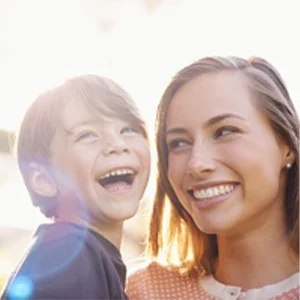 Adult and child standing together outdoors in natural light, facing toward the camer